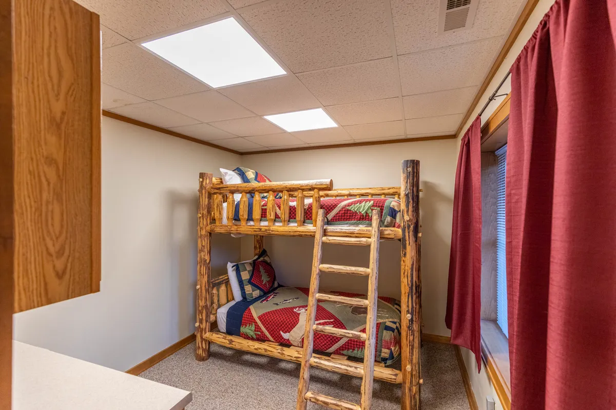 A cheerful bonus sleeping area featuring a bunk bed with colorful quilts and a window with curtains. The playful and practical setup is perfect for kids or extra guests, offering a fun, comfortable place to sleep that’s still connected to the shared areas.